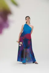 Vestido largo de fiesta con estampado abstracto en tonos azules, fucsia y violetas. Diseño de un solo hombro y falda con suave transparencia.