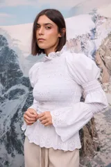 Camisa negra de manga larga con diseño de frunces en el cuerpo y en las mangas, cuello alto y puños con volados.