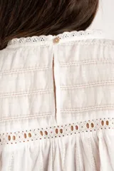 Blusa sin mangas de algodón color blanco, con cuello redondo, detalles de encaje y diseño fruncido en el frente.