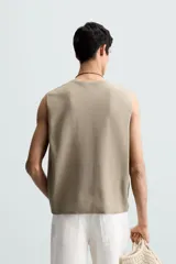 Chaleco de punto color beige claro, con cuello en V y corte relajado sin mangas.