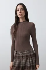 Polera de tejido de punto con textura calada y diseño de líneas verticales acanaladas. Presenta cuello alto y mangas largas con puños delicados, de silueta entallada.