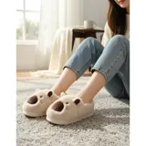 Pantuflas cerradas de peluche color beige con diseño de capibara, incluyendo orejas y nariz bordada. Cuentan con suela antideslizante.