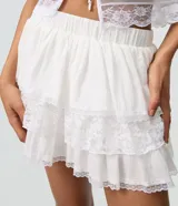 Pollera corta de algodón color blanco, con volados en capas y detalles de encaje floral.