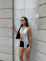 Top blanco con cuello halter, abertura en el frente y lazos para atar.
