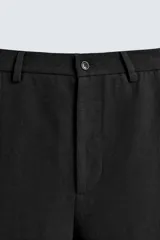 Pantalón de corte recto y ajuste relajado, confeccionado en una mezcla de algodón y lino. Presenta cintura elástica, bolsillos delanteros, bolsillo trasero de plastrón y cierre frontal con cremallera y botón.