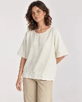 Blusa color crudo de corte holgado, con cuello redondo y mangas cortas amplias que presentan detalle de costuras pespunteadas en los dobladillos.