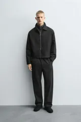 Pantalón regular fit color marrón oscuro, confeccionado en tejido con viscosa. Cuenta con cintura elástica, bolsillos delanteros y detalle de bolsillos traseros de vivo. El cierre frontal es con cremallera y botón.