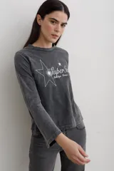 Remera de manga larga con efecto lavado, cuello redondo y estampa frontal con diseño de estrella y texto.