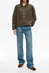 Chaqueta de corte recto y holgado en color verde oliva, confeccionada en tejido de algodón con textura. Presenta cuello camisero, cierre frontal con botones metálicos y dos bolsillos frontales de parche.