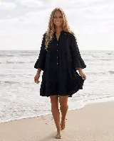 Vestido corto de lino negro con diseño amplio, escote en V con botones frontales, mangas 3/4 con volados y falda escalonada.