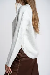 Sweater de punto gris melange con cuello redondo, manga larga y detalle de botones laterales en el costado.