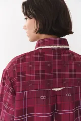 Camisa de corte holgado en color bordó con estampado de cuadros y monograma. Presenta cuello redondo con borde de puntilla, bolsillo frontal con detalle de puntilla, cierre frontal con botones y puños con terminación en puntilla.
