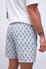 Short de baño celeste con rayas verticales blancas y estampado de flores blancas y azules.