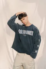 Crewneck de manga larga color gris oscuro con efecto lavado, estampado frontal con el texto "ENDLESS SUMMER" y estrellas estampadas a lo largo de las mangas.
