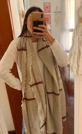 Bufanda de gran tamaño en color beige con diseño de cuadros sutiles en tono bordó y bordes deshilachados.