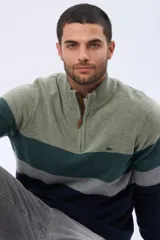 Buzo tejido de punto con diseño de rayas horizontales en tonos verde, gris y azul. Presenta cuello alto con cierre frontal parcial y detalle en material tipo gamuza en la solapa del cierre.