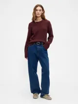 Buzo de tejido suave color taupe, con cuello redondo y puños y ruedo acanalados con diseño de volado en la cintura.