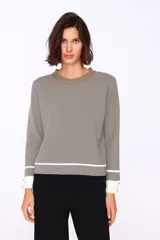 Sweater negro con cuello redondo ribeteado en marrón, corte recto y puños con detalle de botones dorados.