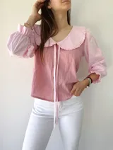 Camisa rosa con mangas 3/4 a rayas y cuello babero con volados.