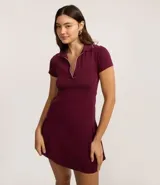 Vestido corto de color bordó confeccionado en tejido rib de algodón. Posee cuello polo con detalle de línea contrastante, escote en V y mangas cortas, con un calce ajustado de estilo deportivo.