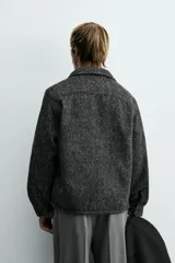 Sobrecamisa de corte relajado confeccionada en tejido con textura efecto pelo. Presenta diseño de cuadros en tonos verde y negro, cuello solapa, cierre frontal con botones, manga larga con puños abotonados y un bolsillo de plastrón en el pecho.