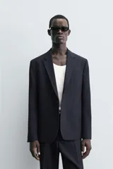 Blazer de corte regular fit confeccionado en tejido con lana. Presenta cuello con solapas de muesca, cierre frontal de un botón, bolsillos de vivo en el pecho y en la cadera, y aberturas en la espalda.