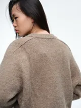 Sweater de tejido suave en tono beige melange, con cuello redondo, mangas largas y corte relajado.
