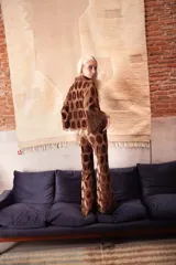 Pantalón de corte evasé confeccionado en tela calada con círculos de terciopelo color marrón. Presenta cintura elástica con cierre para mayor ajuste y comodidad.
