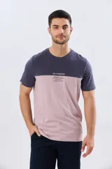 Remera de algodón y poliéster de corte clásico, con diseño en bloques de color negro en la parte superior y gris melange en la inferior. Presenta cuello redondo, mangas cortas y un pequeño estampado tipográfico en el pecho.