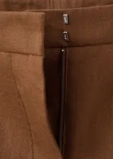 Pantalón marrón de lino, corte recto de tiro medio, con bolsillos laterales y traseros de ribete, trabillas y cierre oculto.