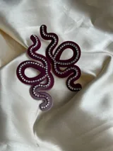 Aros colgantes con forma de serpiente blanca delineada con strass plateado.