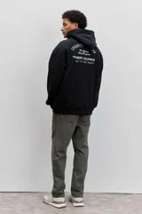 Buzo con capucha y bolsillo tipo canguro, de color crema, con pequeño estampado en el pecho y cordones ajustables en el cuello.