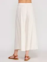 Pantalón palazzo de lino y viscosa, color blanco, de tiro alto y silueta amplia. Presenta pinzas frontales, bolsillos laterales y cierre con botón.