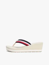 Sandalias tipo ojota con plataforma de cuña alta, color beige claro. Las tiras son de tejido trenzado con las franjas distintivas de Tommy Hilfiger (azul marino, blanco y rojo).