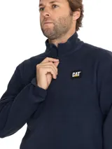 Buzo de polar tipo microfleece color azul marino, con cierre frontal de cuarto de longitud y cuello alto. Presenta el logo de la marca Caterpillar bordado en el pecho.