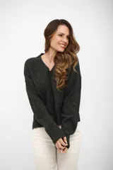 Buzo de punto color gris oscuro, con escote en V, manga larga y hombros caídos. Presenta un diseño holgado con terminaciones acanaladas en puños y ruedo.