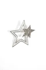 Broche plateado con forma de estrella de dos capas. La estrella más grande tiene un borde plateado brillante y un centro blanco. La estrella más pequeña está cubierta de strass plateado.