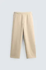 Pantalón jogger de corte relajado y pernera ancha, confeccionado en tejido de algodón con interior perchado. Cuenta con cintura elástica ajustable mediante cordón interior, bolsillos laterales y un bolsillo trasero de plastrón.