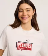 Remera blanca de algodón con estampa gráfica en la espalda inspirada en un club de jazz, con personajes de Peanuts (Snoopy, Lucy, Linus y Woodstock) y el texto "THE PEANUTS LOUNGE JAZZ AND UPPER LIVE CLUB MUSIC".