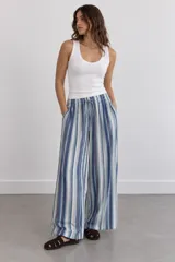 Pantalón largo de corte ancho, con diseño de rayas verticales en tonos azules, celestes y blancos, cintura elástica con cordón ajustable y bolsillos laterales.