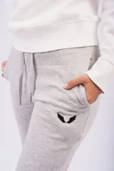 Pantalón de jogging color gris oscuro con efecto lavado, confeccionado en frizza de algodón. Presenta un diseño relajado con bolsillos laterales y un detalle bordado de alas en la parte frontal.