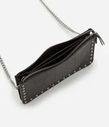 Cartera bandolera Satinato de color marrón oscuro, confeccionada en poliuretano con textura geométrica símil cocodrilo y detalles de tachas metálicas plateadas en los bordes. Cuenta con cierre superior y correa larga de cadena metálica.