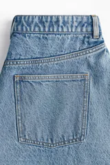 Pollera mini de denim de algodón rígido, color celeste claro con efecto lavado. Diseño acampanado con cintura estándar, cierre frontal con botón y cinco bolsillos.