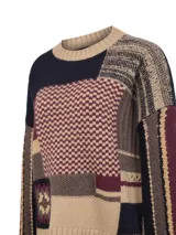 Sweater de lana con diseño patchwork que combina diversos patrones de tejido y bloques de color en tonos tierra, bordó y azul marino. Presenta cuello redondo, mangas largas y terminaciones en rib.
