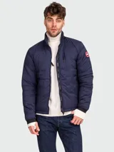 Campera acolchada azul marino marca Canada Goose, modelo Lodge, con cierre frontal, cuello alto y logo en el brazo.