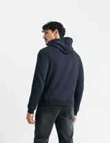 Sweater deportivo con capucha, bolsillo canguro frontal y cordones de ajuste. Presenta un diseño de color azul oscuro con interior de capucha en color verde.