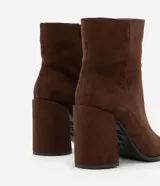 Bota de caña corta con acabado aterciopelado, punta cuadrada y taco bloque alto. Presenta un diseño minimalista y estructurado con cierre lateral.