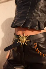 Cinturón de cuero negro con hebilla metálica dorada en forma de sol con rayos.
