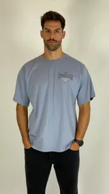 Remera de manga corta color azul grisáceo, con cuello redondo y estampa gráfica en el pecho.