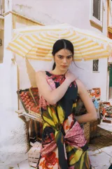 Vestido midi de popelina con cuello redondo, diseño sin mangas de corte semi-halter y lazos frontales para atar a la cintura. Estampado multicolor con motivos de mangos y flores.